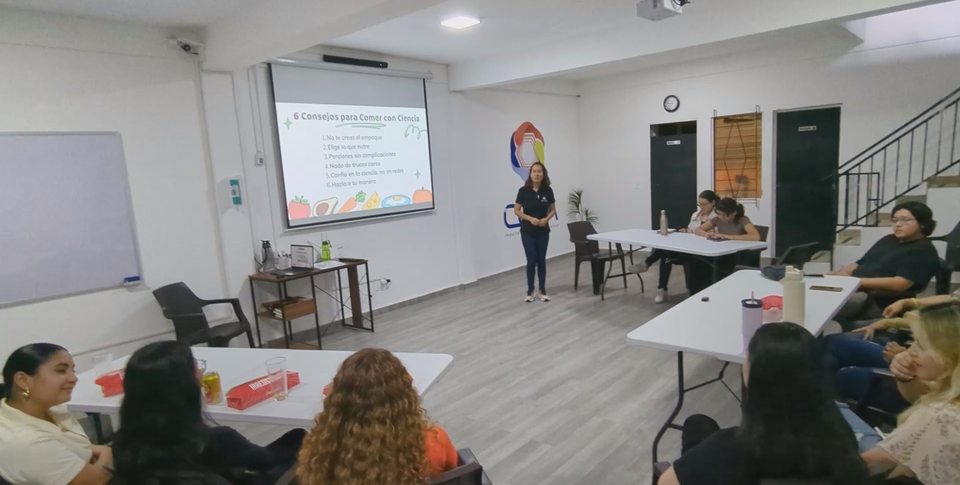 Yanira Useche de pie, frente a la lámina Seis consejos para comer con ciencia.